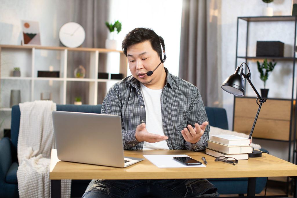 Asian man using headset and laptop for video chat