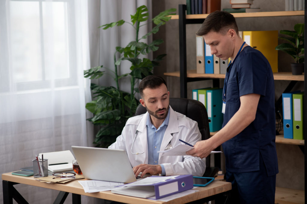 Bearded head doctor reviewing the report of young intern